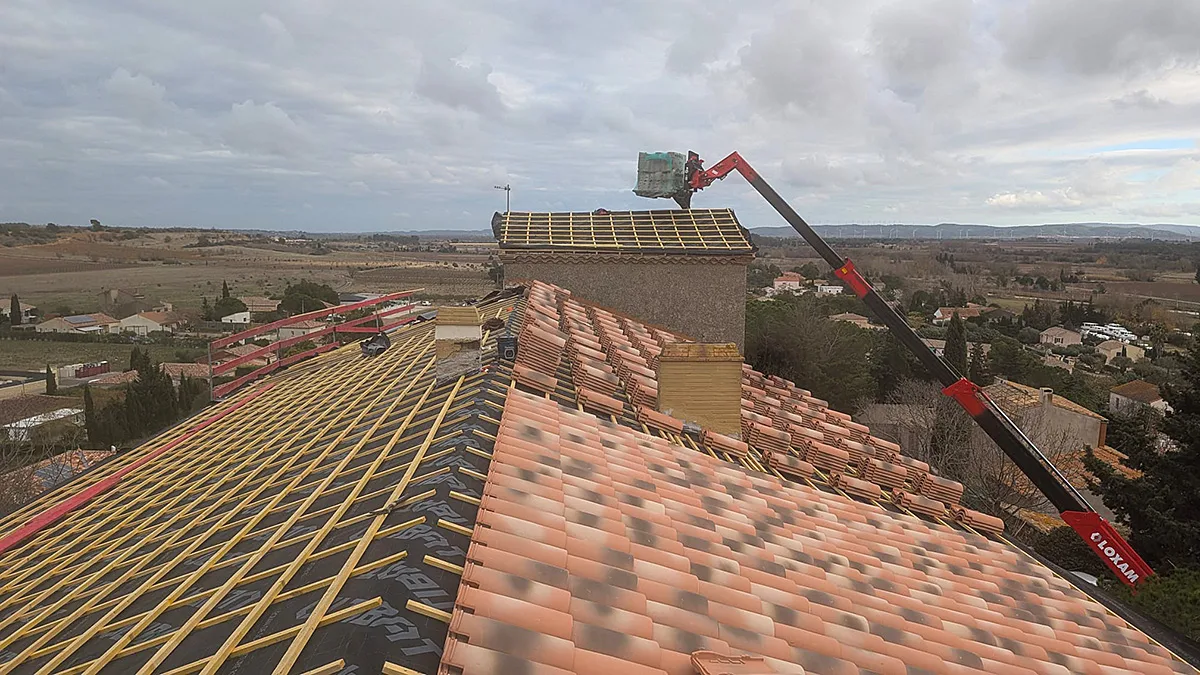 Grue de chantier livrant des matériaux sur le toit en cours de rénovation